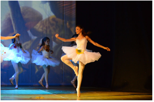 Ballerina classica in primo piano esegue un elegante retiré sulla punta durante lo spettacolo "Alice nel Paese delle Meraviglie" del Centro di Produzione Danza e Recitazione Viterbo